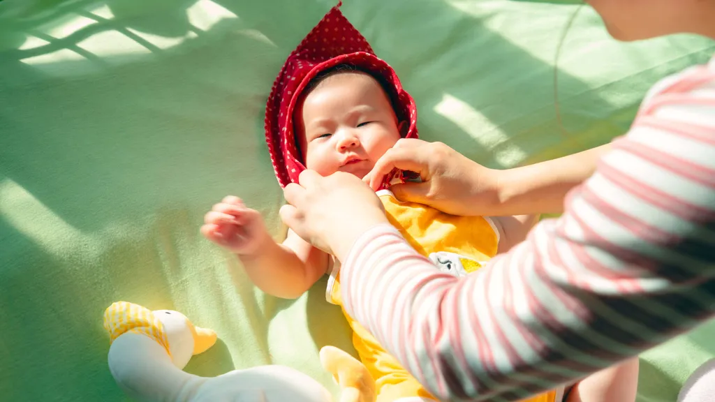 妈妈的手正在给宝宝系红头巾的带子